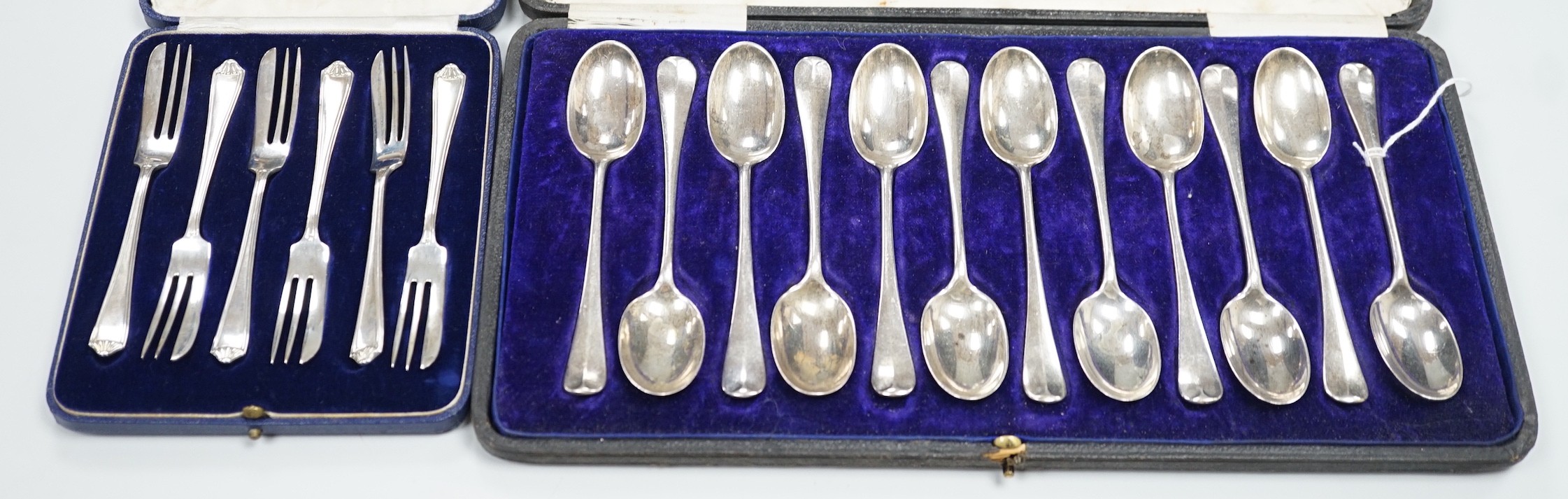 A cased set of twelve George V silver rat-tail pattern teaspoons, William Hutton & Sons, Sheffield, 1915 and a similar cased set of six pastry forks by Mappin & Webb, 13.1oz.